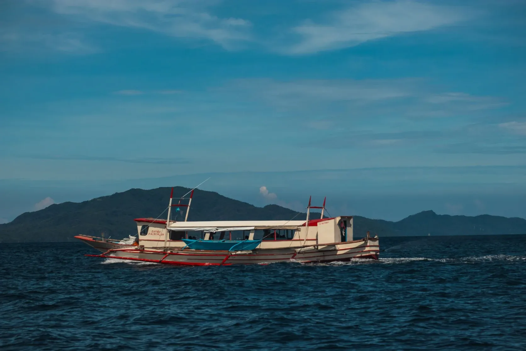 Un bateau de pêche naviguant sur une mer calme au pied des montagnes.