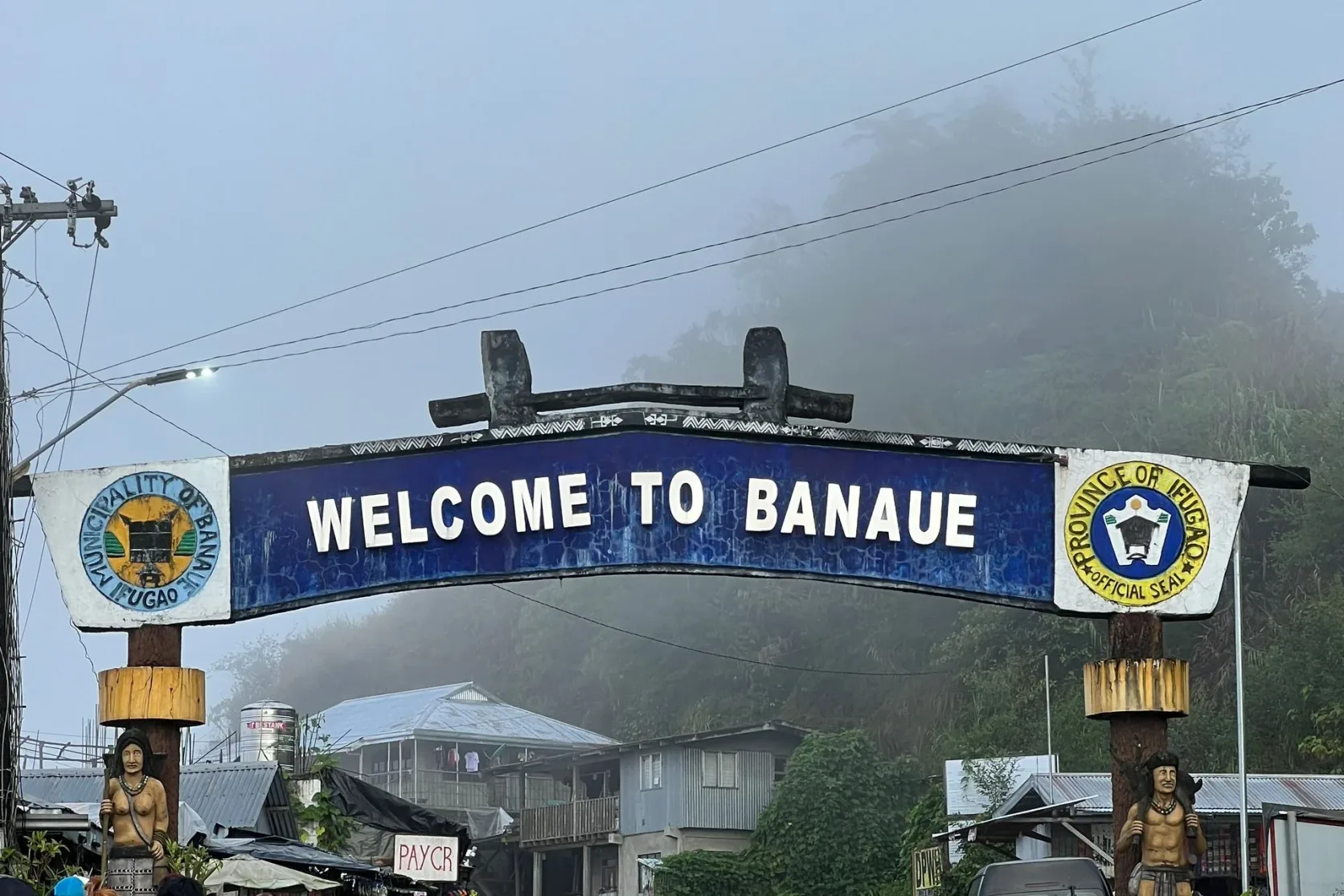 Des gens sous le portique Welcome to Banaue dans le brouillard.