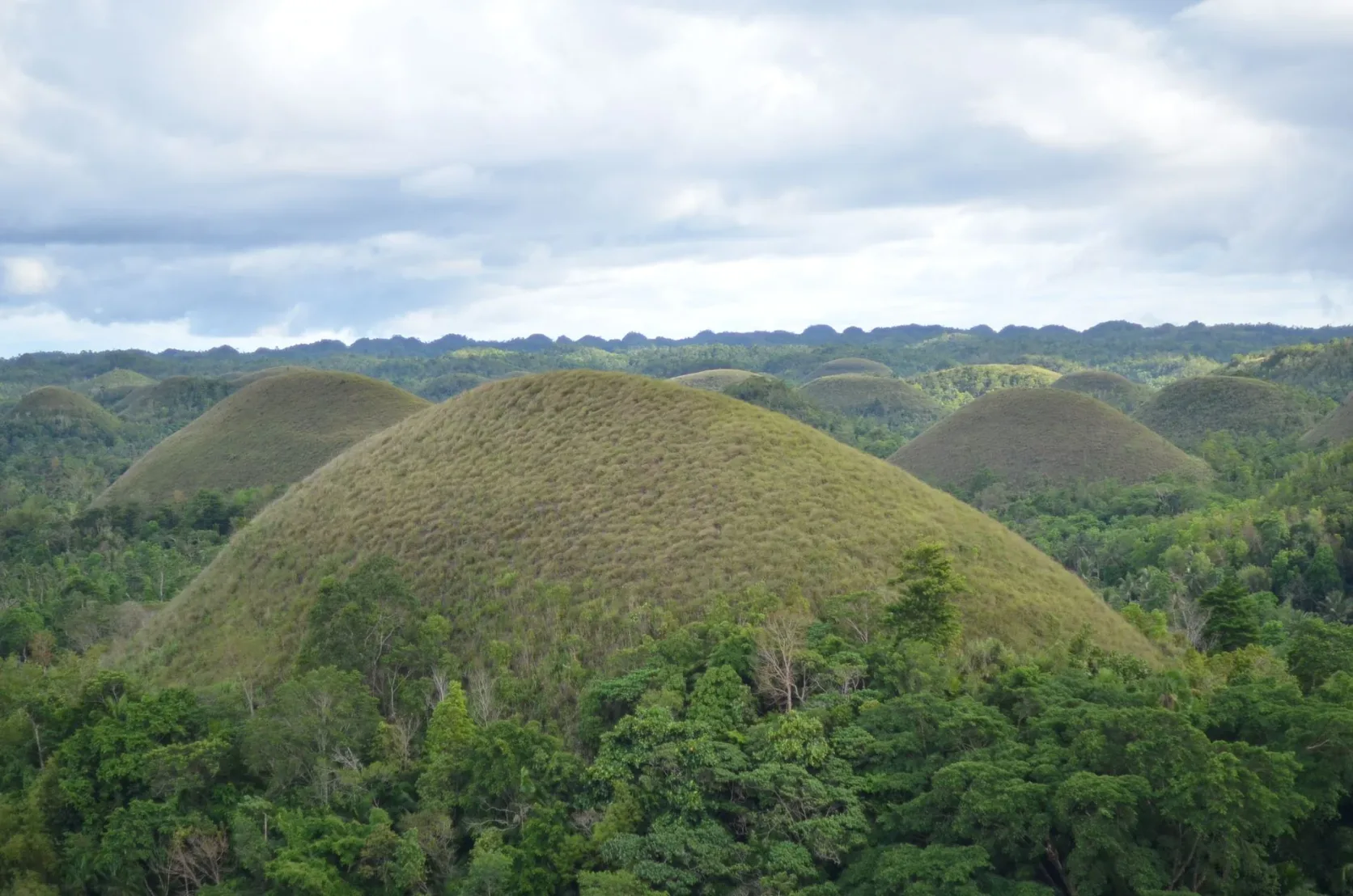 Les Chocolate Hills de Bohol sous un ciel nuageux.