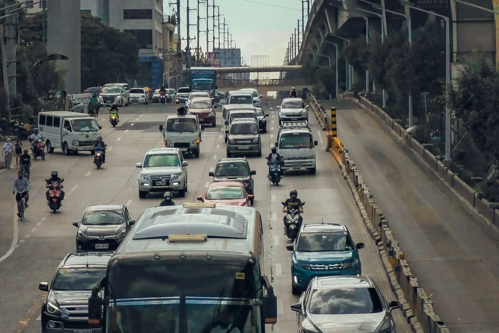 Des bus et des voitures sur une autoroute philippine sous un échangeur.