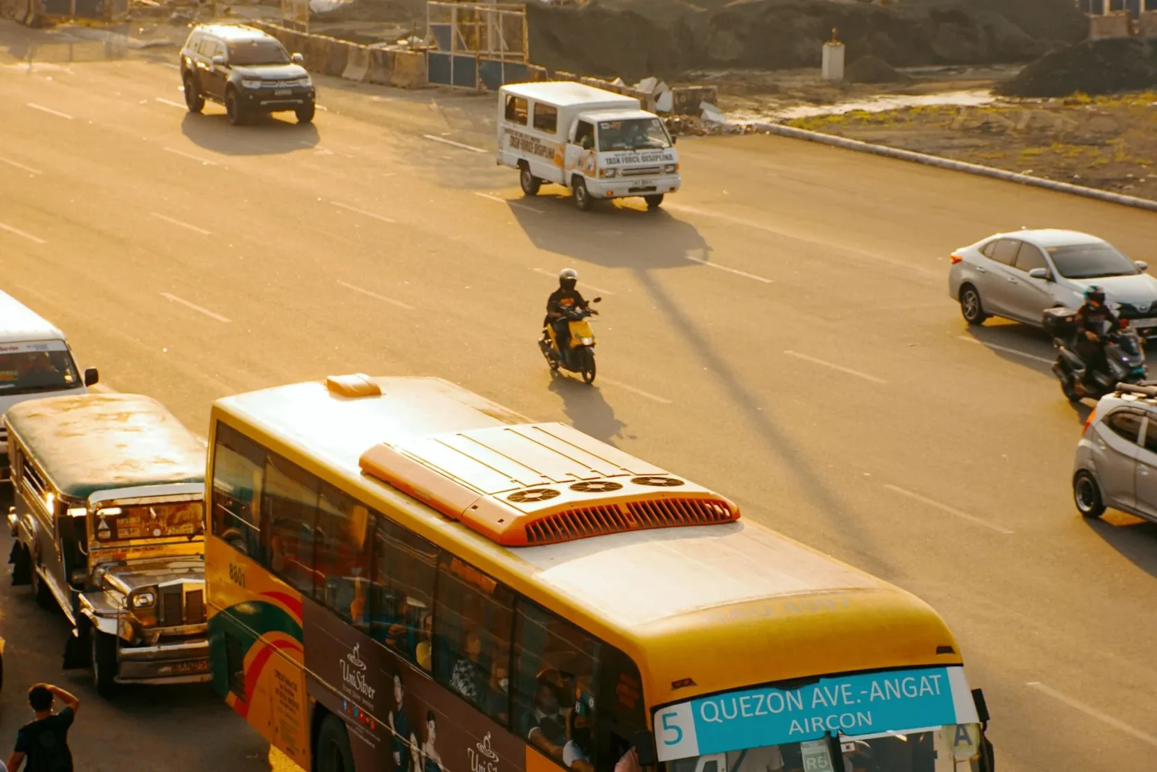 Des bus, des jeepneys et des voitures sur Quezon Avenue au coucher du soleil.