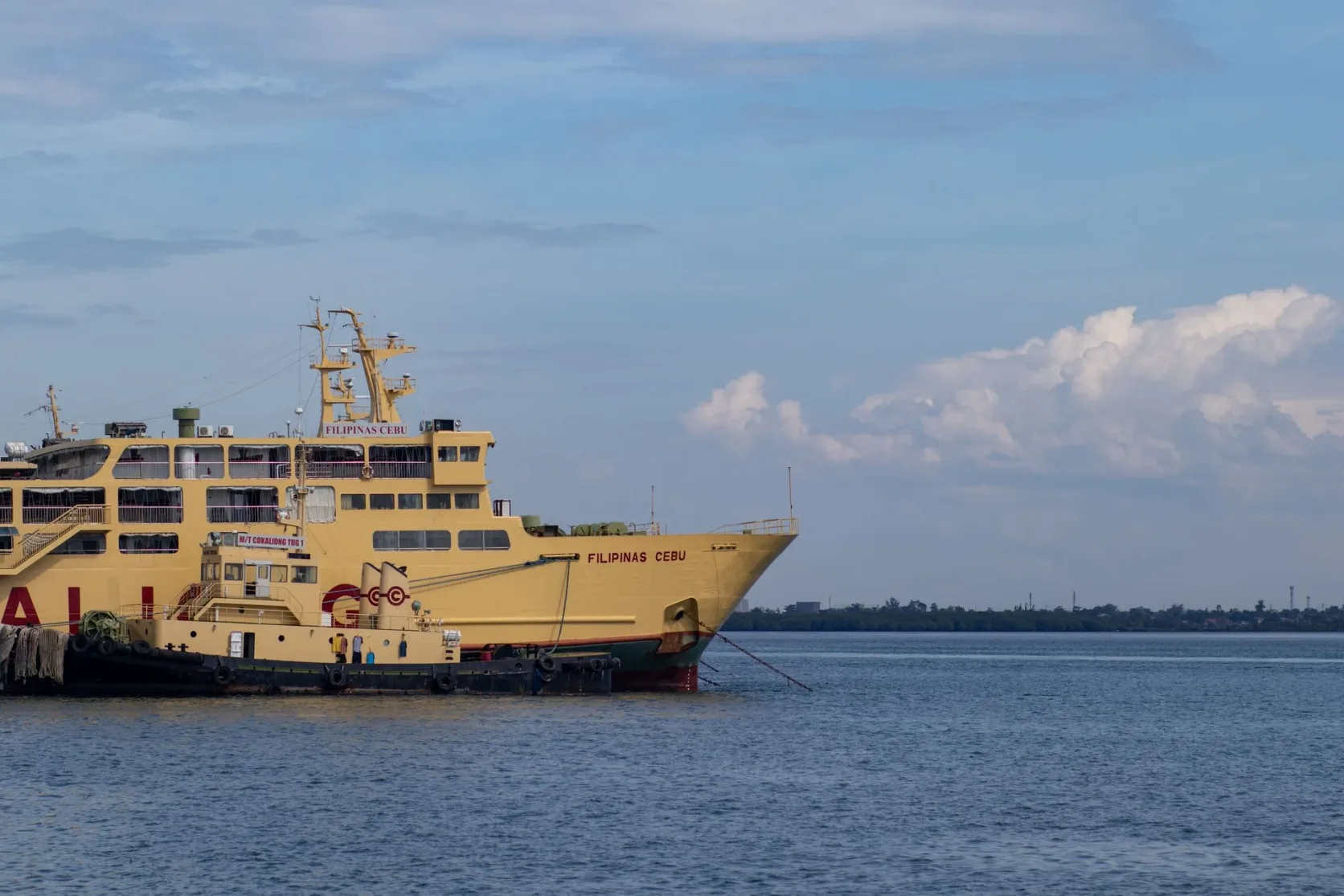 Un ferry jaune, le Filipinas Cebu, à l'ancre sur une mer calme.