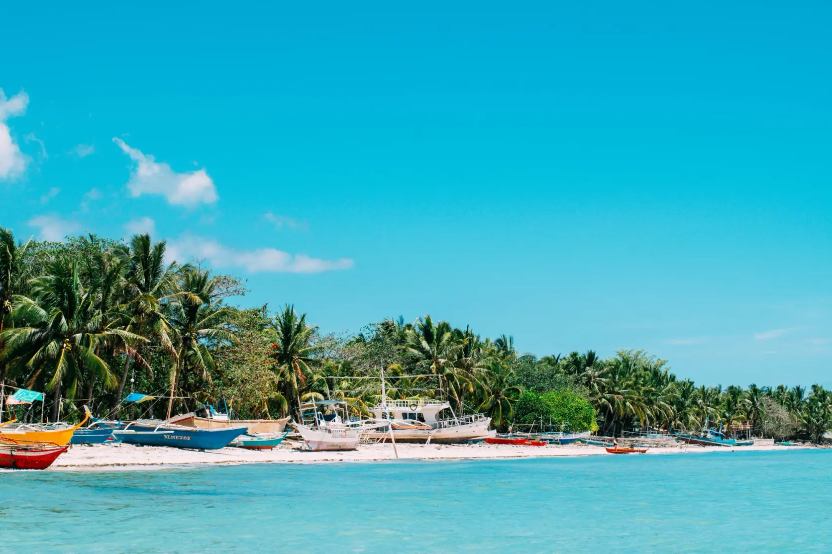 Outrigger boats pulled up on a white-sand beach on Bantayan Island.