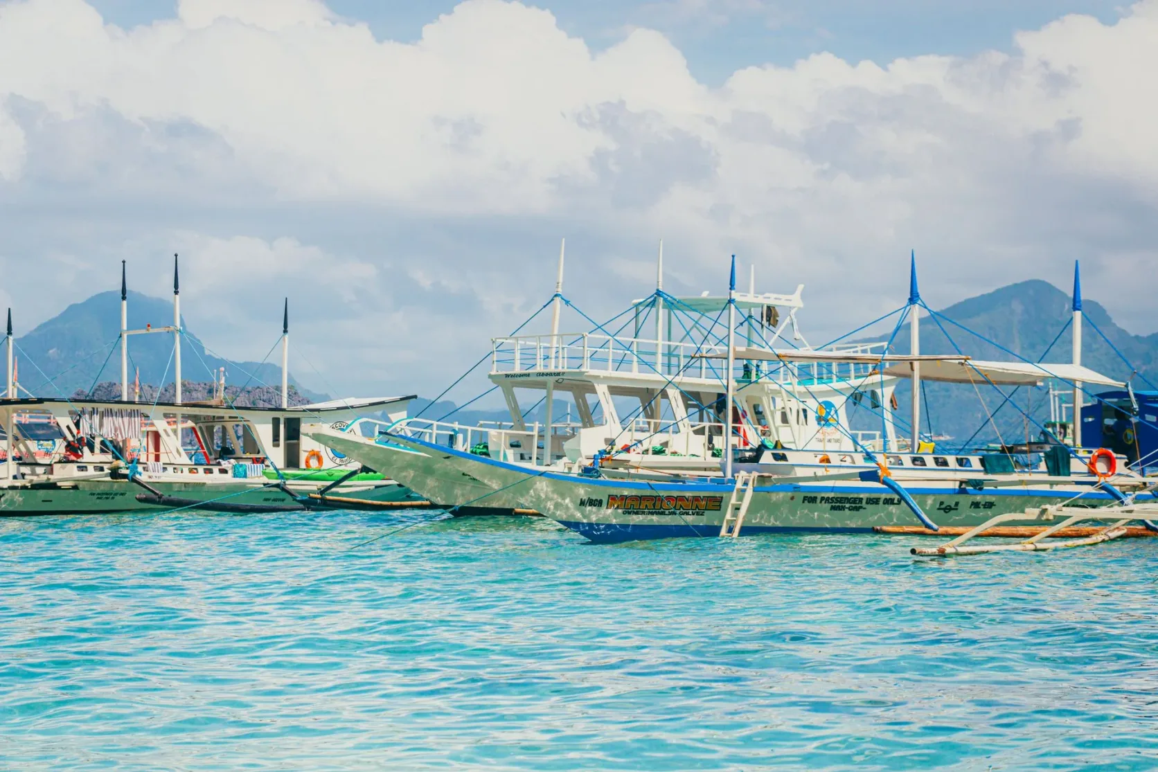 Des pirogues à balancier amarrées dans un port philippin sous les collines.