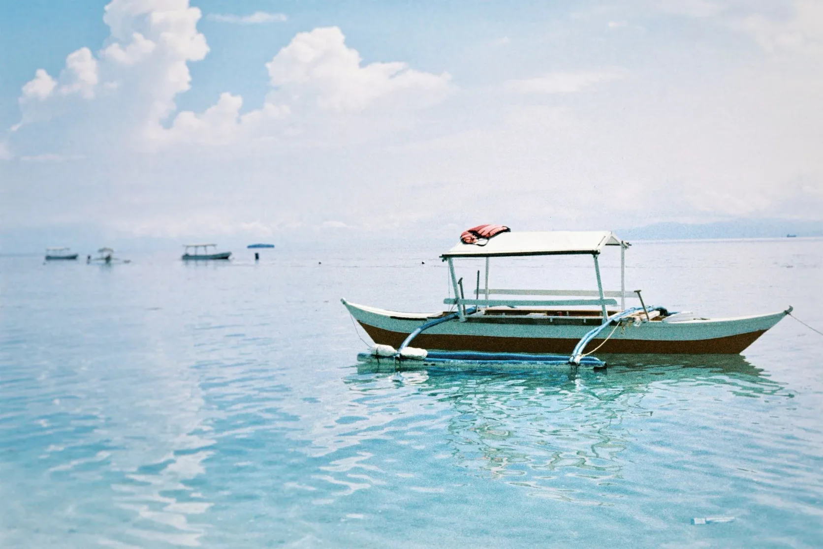 Une bangka à balancier sur une eau bleue et transparente.