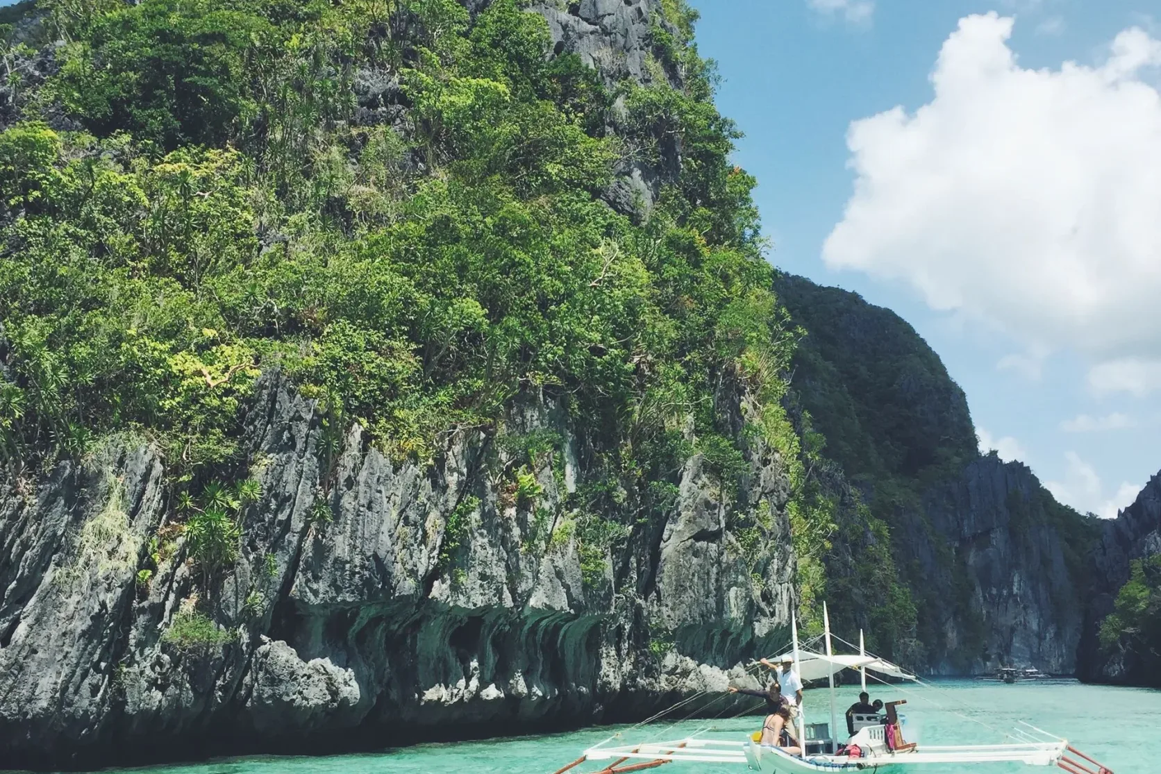 Un bateau d'excursion passant devant les falaises d'El Nido.