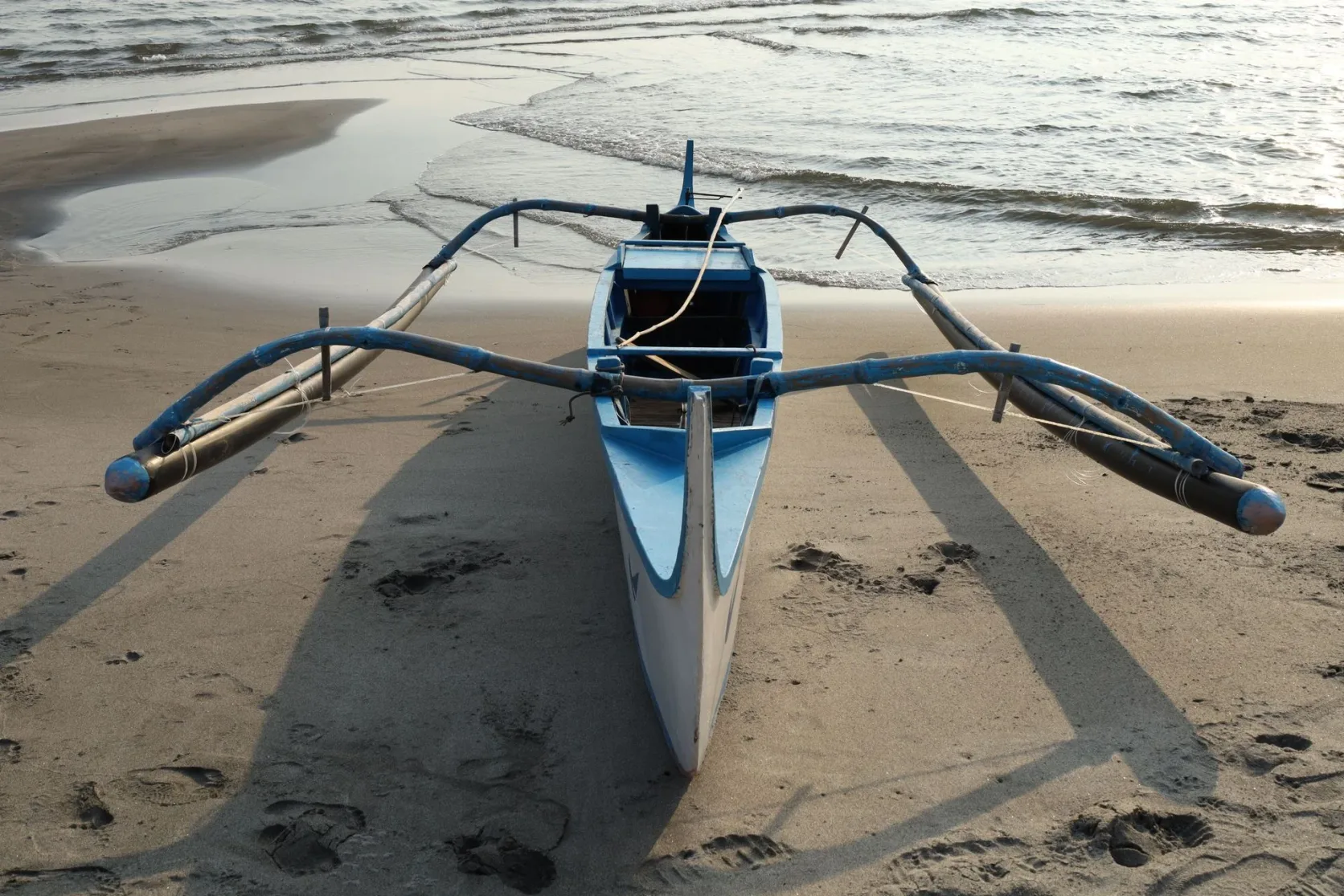 Une pirogue à balancier sur une plage de sable philippine.