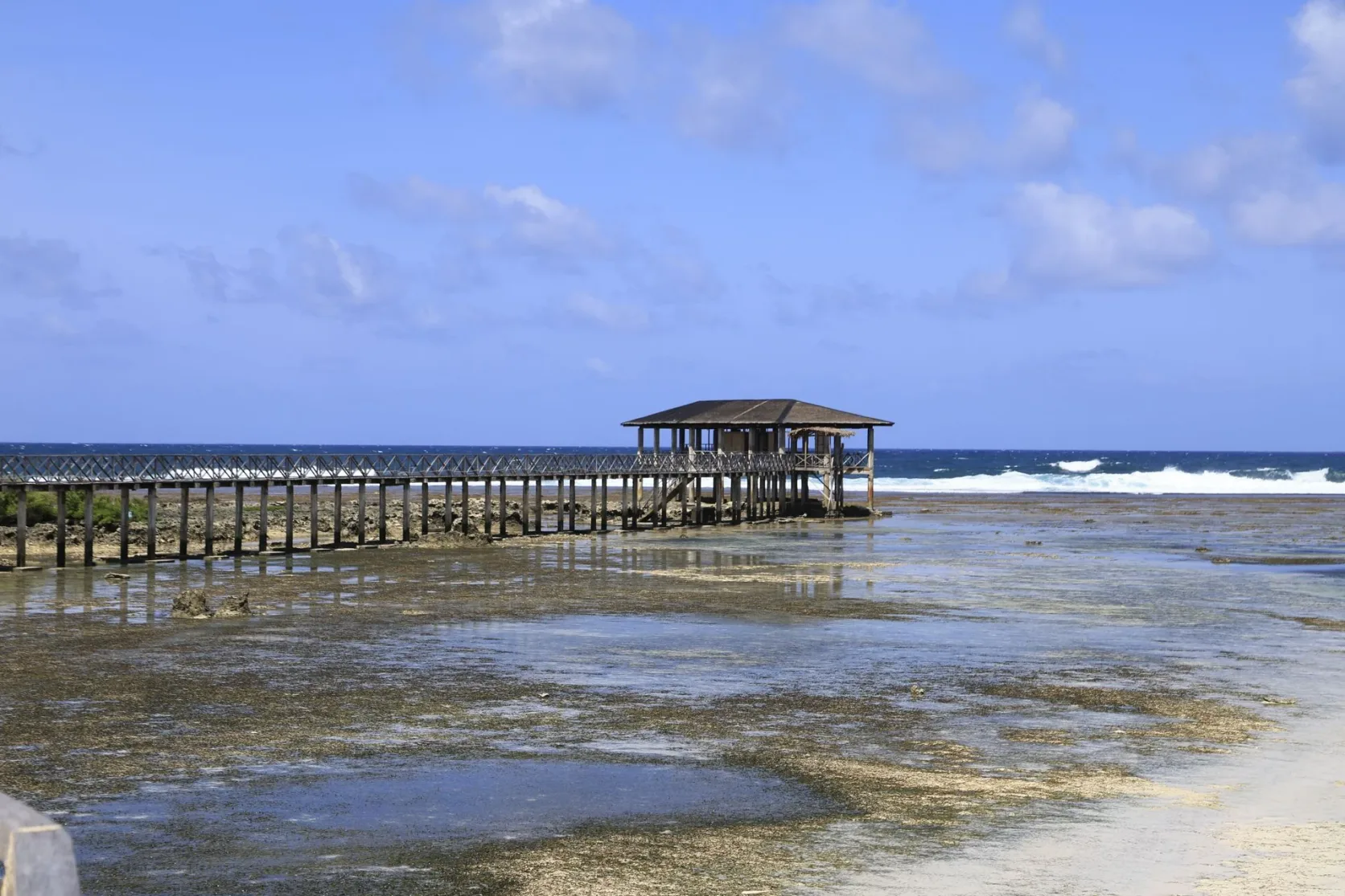 Un ponton en bois couvert de chaume au-dessus de la mer.